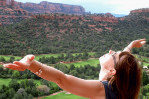 Woman opening her arms to the sky and the red rocks of Sedona