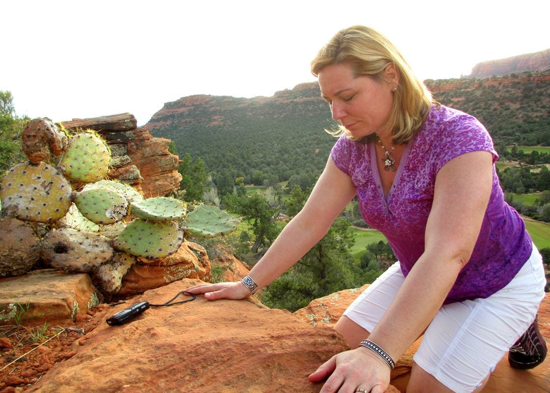 Woman feeling the energy of the red rocks in her hands on a Sedona Vortex Retreat
