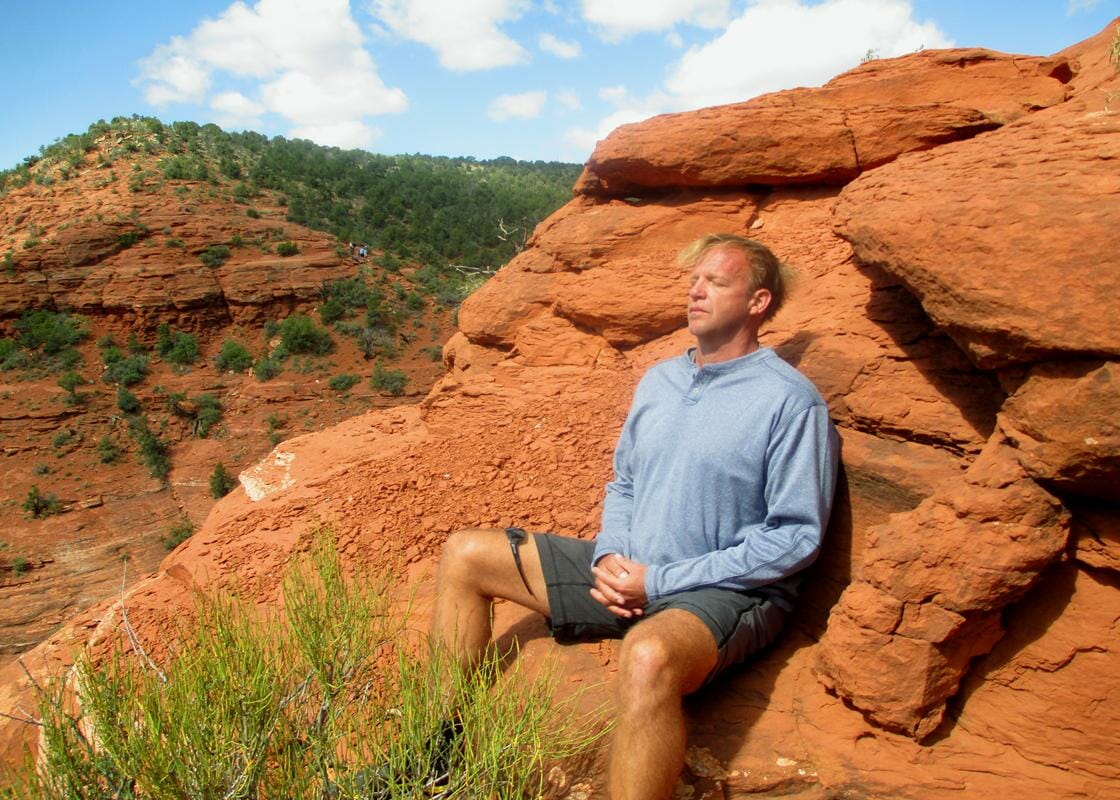 Man meditating on the red rocks during a Sedona Vortex Retreat