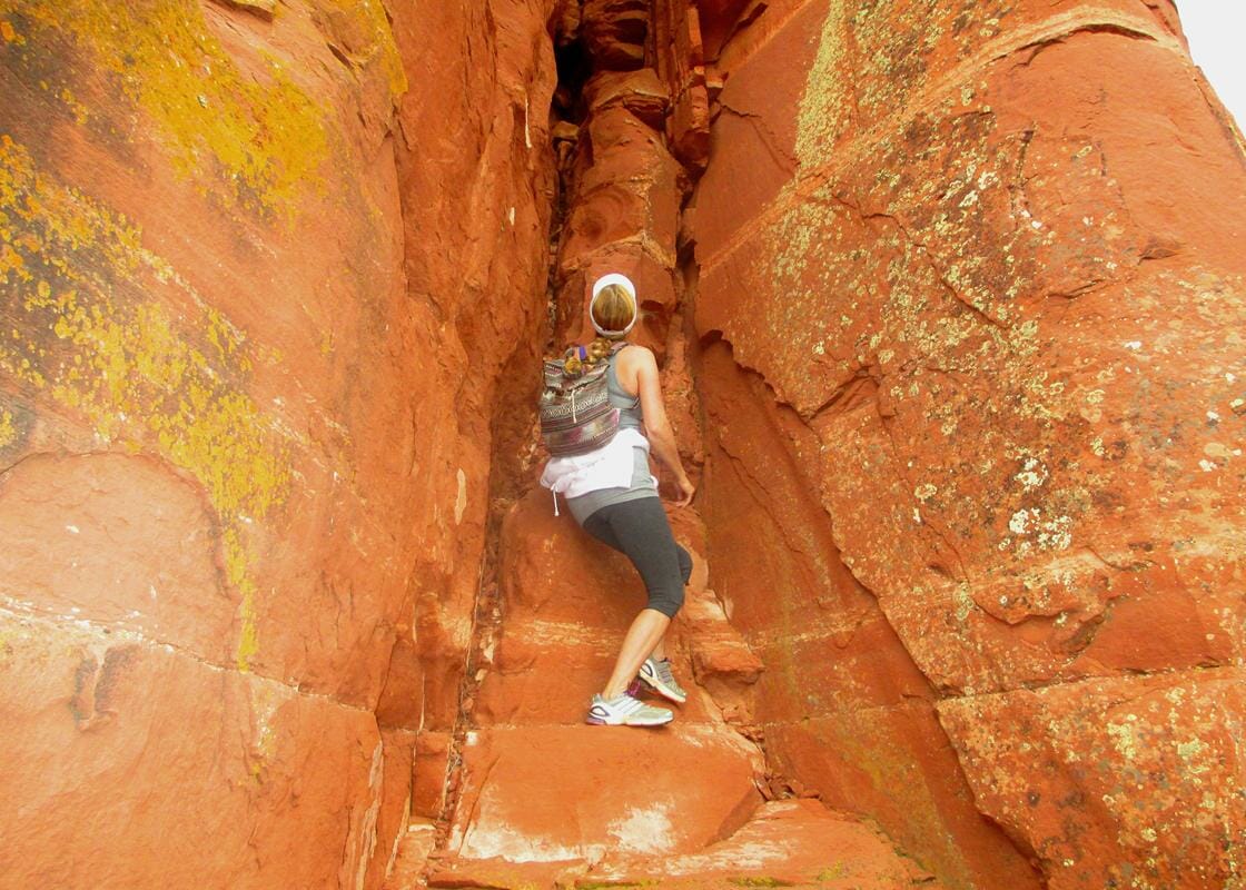 Woman on a Shamanic journey retreat climbs the channel of a red rock