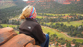 A woman overlooks Verde Valley from the heights of a red rock