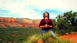 Smiling woman holding a crystal and looking skyward on the red rocks during a Sedona Vortex Retreat